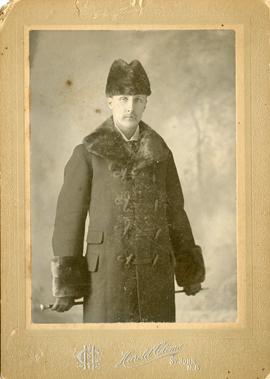 Wessie Newton, as a middle aged man, standing dressed in winter coat trimmed at collar and cuffs ...